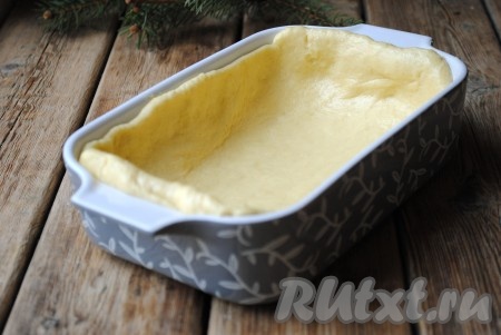 Жаропрочную форму смазать сливочным маслом или застелить пергаментом. Тесто разделить на две равные части. Одну часть раскатать и выстелить дно и бока формы. 