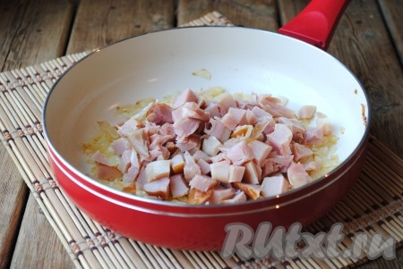 Копчёное мясо нарезать кубиками, выложить к обжаренному луку, перемешать и готовить ещё 2 минуты, помешивая.&nbsp;
