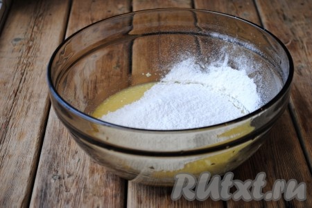 Всыпать разрыхлитель, порциями начать добавлять просеянную муку, вначале перемешивая тесто ложкой, а когда тесто начнёт собираться в ком, продолжить замешивать его руками.