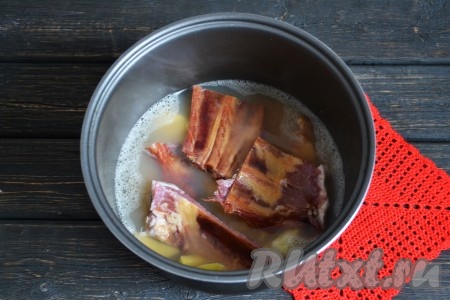 Сразу же выложить и копченые ребрышки, нарезанные на небольшие порционные части. Вместо ребрышек можно использовать и другие копчености, например, колбасу. Закрыв крышку мультиварки, включить режим "Суп" ещё на 20 минут.
