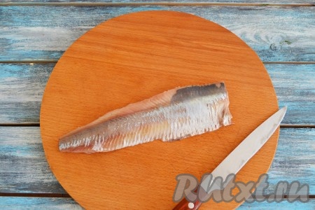 Если сельдь замороженная, её нужно разморозить. Подготовить филе сельди: отрезать голову и хвост, удалить внутренности, вымыть, обсушить, снять кожицу и тщательно вынуть косточки.
