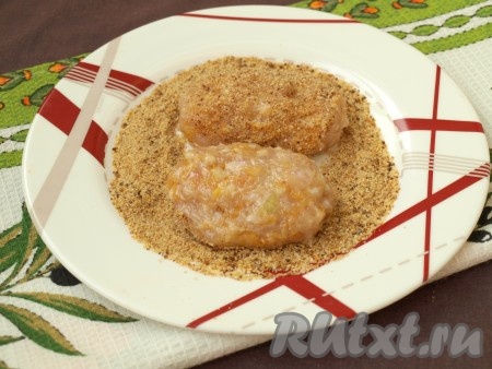 На тарелку насыпать панировочные сухари (или муку), сформировать из фарша курино-тыквенные котлеты и обвалять их со всех сторон в сухарях (или муке).