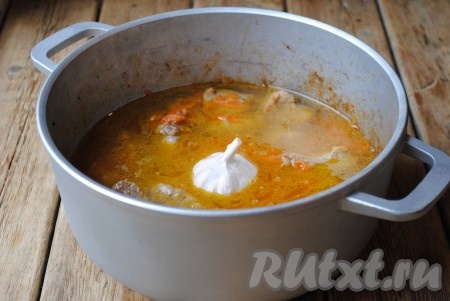 Влить холодную воду так, чтобы она покрыла содержимое казана, кроме чеснока. Довести до кипения и готовить под крышкой на медленном огне 40 минут.
