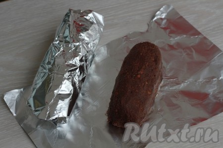 Разделить массу на 2 части. Из каждой части сформировать шоколадную колбасу. Завернуть каждую колбаску в фольгу и убрать в холодильник до застывания (как минимум на 2-3 часа). Чтобы масса стала ровной со всех сторон, нужно в процессе застывания достать колбаски из холодильника и прокатать по столу.