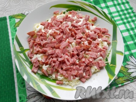 Колбасу нарезать мелкими кусочками (кубиками). Если вареная колбаса - ее можно натереть на крупной терке. Колбасу выложить следующим слоем + немного майонеза.
