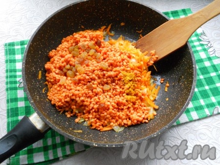 Добавить чечевицу, порошок карри, черный свежемолотый перец и промытый изюм в сковороду к обжаренным овощам. 