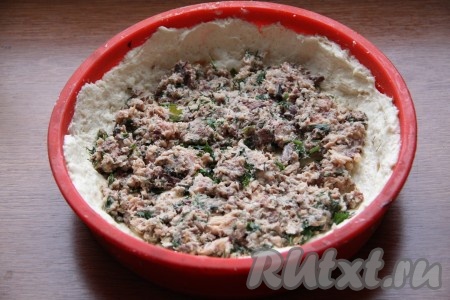 Для приготовления начинки рыбные консервы из банки без масла выкладываем на отдельную тарелку, удаляем косточки. Разминаем рыбу вилкой и смешиваем с мелко нарезанной зеленью. Получившуюся начинку равномерно выкладываем на тесто.