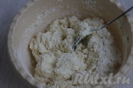 Добавить муку, перемешать ещё раз. Тесто получится липким, но достаточно плотным, таким чтобы можно было скатать шарики. Количество муки будет во многом зависеть от влажности творога, поэтому в тесто может потребоваться добавить ещё немного муки.