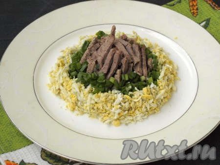 Натереть на тёрке яйца, выложить их кольцом вокруг лука.
