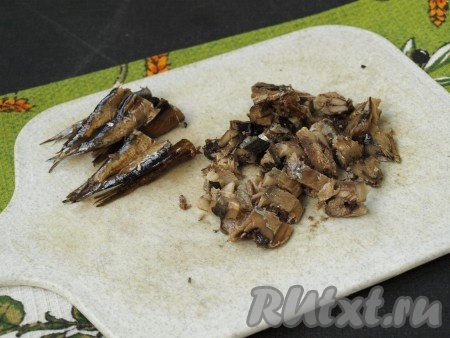 У шпрот отрезать хвостовую часть длиной около 4 сантиметров (эта часть потребуется нам для украшения). Оставшуюся часть шпрот нарезать кусочками.