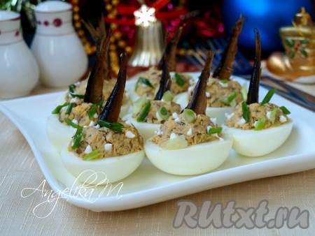 По центру вставить отложенные части шпрот хвостиками вверх, будто рыбка "нырнула". Сверху поставить капли майонеза, но это непринципиально, можно майонез не использовать вообще. Измельчить зелёный лук и посыпать немного яйца сверху. Очень вкусные и красивые яйца, фаршированные шпротами и желтками, подать к столу.