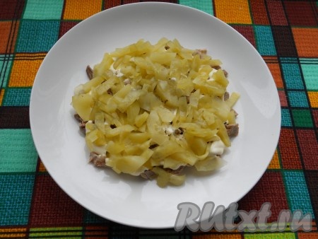 Маринованные огурцы нарезаем соломкой (или на небольшие кусочки). Равномерно выкладываем поверх свинины половину нарезанных огурцов.