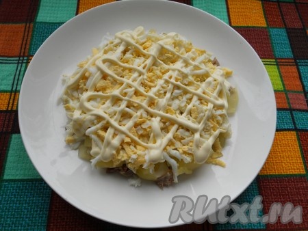 Яйца натираем на крупной тёрке. Следующим слоем салата выкладываем половину натёртых яиц, солим, смазываем майонезом.