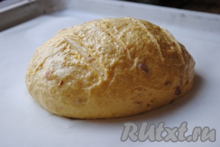 Когда тесто подойдёт во второй раз, его нужно ещё раз обмять и сформировать круглую заготовку хлеба. Острым ножом сделать на поверхности несколько надрезов. Выложить тесто на противень, застеленный пергаментом, и дать постоять в тепле 20 минут.&nbsp;
