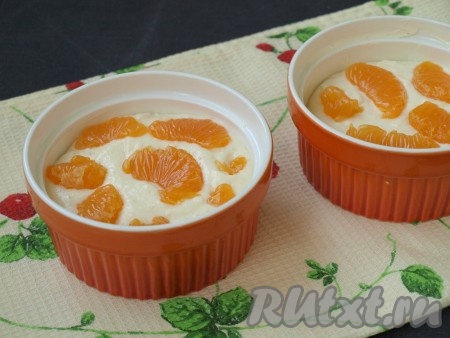 Дно и бока большой формы (или 2 порционных формочек) смазать сливочным маслом. Выложить половину творожной массы в форму (или формочки). Мандарины очистить и разобрать на дольки. Каждую дольку освободить от плёночек и удалить, если есть, косточки. Разложить половину долек мандаринов поверх творожной массы, слегка утапливая фрукты.