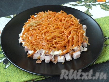 Полоски моркови по-корейски разрезать на 3-4 части, затем равномерно выложить поверх ветчины.