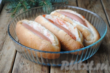 Каждую булочку разрезать вдоль, не дорезая до конца, чтобы получился кармашек. Внутри булочку смазать кетчупом, майонезом и горчицей, количество соуса можно регулировать по своему вкусу. Сосиски освободить от оболочки и выложить в булочки. Поместить хот-доги в жаропрочную форму и отправить в духовку, разогретую до 180 градусов, на 10 минут. 