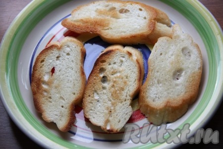 Батон или чиабатту нарезать на порционные ломтики и обжарить с одной стороны на сковороде с добавлением растительного масла. Остывшую обжаренную сторону натереть зубчиком чеснока. Для данного количества начинки мне понадобилось 6 кусочков обжаренного хлеба.
