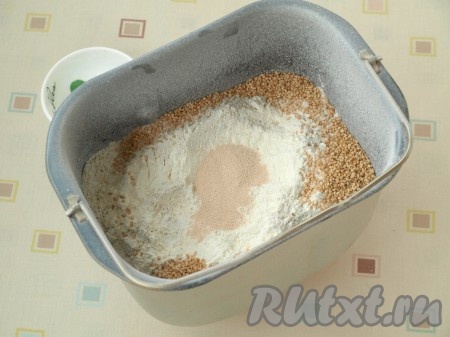 Насыпаем просеянную ржаную и пшеничную муку, по углам раскладываем кунжут и соль. В центре делаем углубление и всыпаем туда сухие дрожжи.
