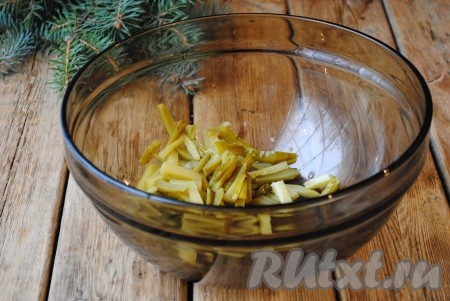 Пока картошка остывает на бумажном полотенце, можно заняться формирование салата "Гнездо глухаря". Солёные (или маринованные) огурцы нарезать соломкой и выложить в миску.