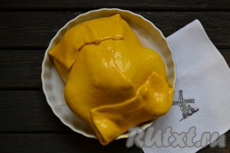 Свисающие края теста свернуть конвертиком (как на фото), полностью закрывая курицу. Отдельно смешать одно яйцо с щепоткой соли и смазать всю поверхность теста.
