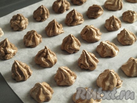 Застелить пергаментом противень. Белково-шоколадную массу аккуратно переложить в кондитерский мешок с насадкой "звёздочка". Выдавить пирамидки размером с грецкий орех (если нет кондитерского мешка, можно выкладывать безе на застеленный противень ложкой). Между пирожными должно быть расстояние около 3 см, так как при выпекании шоколадное безе увеличится в размере.