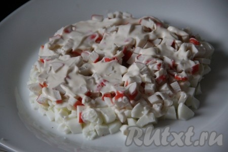 Следующим слоем выложить нарезанные крабовые палочки и тоже смазать майонезом.
