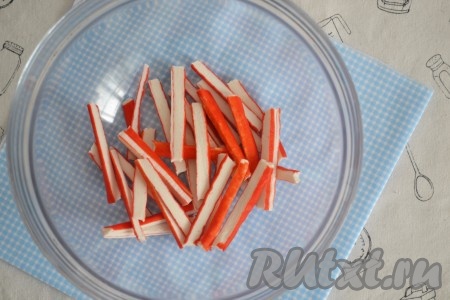 Белую фасоль залить водой (в пропорции 1:3) и при слабом кипении, не накрывая крышкой, варить до полной готовности, примерно, 45-50 минут. Крабовые палочки нарезать тонкой соломкой.
