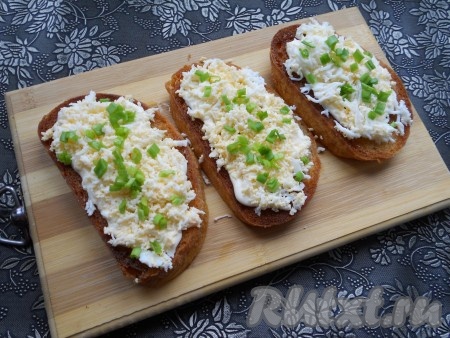 Посыпать натертыми яйцами все обжаренные гренки. Сверху украсить измельченным зеленым луком.
