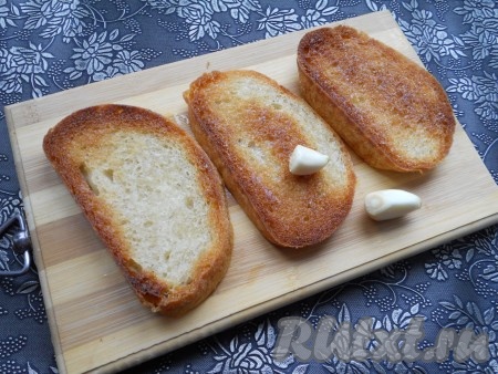 Гренки немного остудить и натереть обжаренную сторону чесноком.