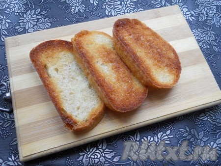 Обжарить ломти батона на растительном масле до румяности с одной стороны.
