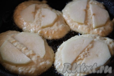 На разогретую сковороду влить немного растительного масла, раскалить. Затем выкладывать столовой ложкой тесто на сковороду в виде оладий. На один оладушек нам понадобится 1 столовая ложка теста. 1 яблоко, очистив от кожуры и семечек, нарезать на тонкие ломтикам и выложить сверху на тесто.