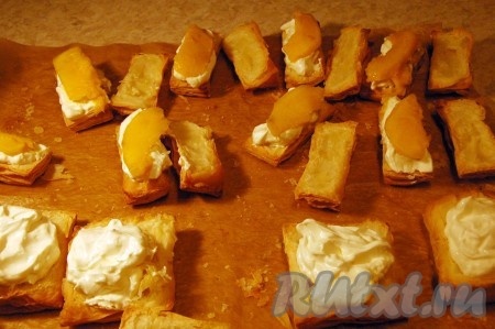 Теперь берем каждую половинку испеченного теста и густо смазываем взбитыми сливками. Поверх сливок размещаем кусочек манго.