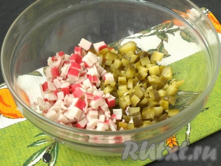 Крабовые палочки и маринованные огурцы нарезать кубиками, сложить в глубокий салатник. Если желаете украсить салат, оставьте часть палочек для оформления.
