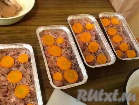 Мясо разбираем на волокна, тщательно руками прощупываем, чтобы не было мелких костей! Кожу, жир и хрящи - не используем! Затем нарезаем мясо на мелкие кусочки и выкладываем в емкости для холодца, положив сверху кусочки вареной морковки. Распределяем мясо по подготовленным емкостям, чтобы его количество было равномерным. Емкости должны быть практически заполнены до верха. Если любите чеснок - можно посыпать немного мелко нарезанным чесночком.
