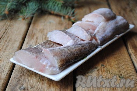 Если хек замороженный, его надо разморозить, хорошо вымыть под проточной водой и разделать на филе. Для того чтобы разделать на филе, надо обрезать кухонными ножницами плавники, а затем острым ножом, начиная от хвоста, срезать мясо вдоль хребта, перевернуть рыбу и повторить процедуру с другой стороны. Подготовленное филе разрезать на порционные кусочки. Филе хека посолить по вкусу, добавить приправу к рыбе, по желанию можно сбрызнуть лимонным соком. Оставить рыбу мариноваться на 10-15 минут.