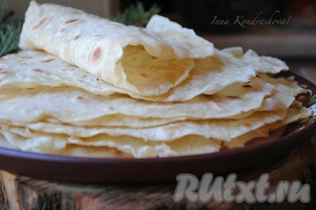 Готовую пшеничную тортилью снять со сковороды и немного сбрызнуть водой, накрыть полотенцем, это нужно для того, чтобы лепёшка стала мягкой и было удобно заворачивать в неё начинку. Аналогично пожарить оставшиеся тортильи. Вкусные лепёшки готовы к употреблению, их можно подавать с начинкой или без. Также их можно хранить в холодильнике, завернув в плёнку, и разогревать при необходимости.&nbsp;
