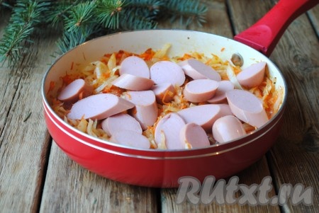 Когда капуста будет практически готова, очищенные от оболочки сосиски, нарезанные кружочками толщиной 0,5 см, добавить на сковороду.
