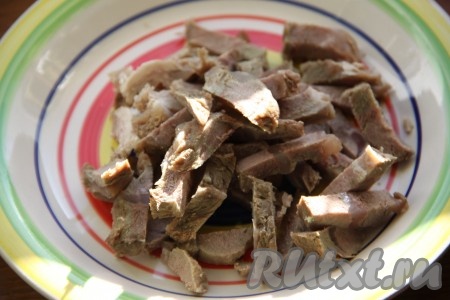 Свинину для салата нужно предварительно отварить до готовности в воде с добавлением горошин чёрного перца, лаврового листа и соли (варить мясо, примерно, в течение 1 часа). Мясо должно быть лишь слегка соленым, основная соль будет в заправке. Отварную свинину нарезать брусочками.