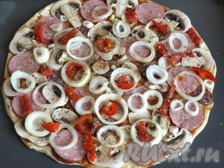 Кружочками нарезать лук, разложить его сверху колбасы с грибами, посыпать пиццу сухим орегано. Я ещё добавила консервированный перец, можно также взять помидоры.
