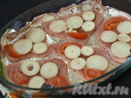 В форму для запекания выложить на дно фольгу и смазать растительным маслом, чтобы мясо не пристало. Сверху выложить отбивные из индейки, на них - кружочки лука и ломтики помидоров.
