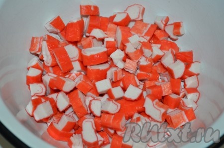 Крабовые палочки заранее разморозить. Снять с них слюду и нарезать на кусочки.