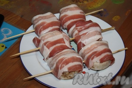 Каждый шампиньон обернуть ломтиком бекона (или двумя ломтиками), нанизать на шпажки так, чтобы бекон не развернулся.
