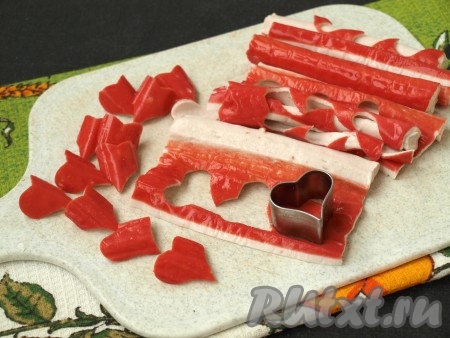 Развернуть крабовые палочки и с помощью формочки вырезать сердечки. Этот шаг можно пропустить, если вам не нужно украшение.
