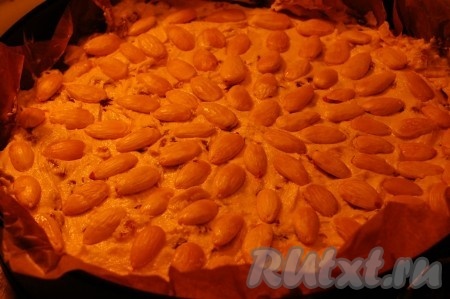 Форму выложить изнутри бумагой для выпечки и вылить в нее тесто. Поверх теста выложить целые дольки миндаля.