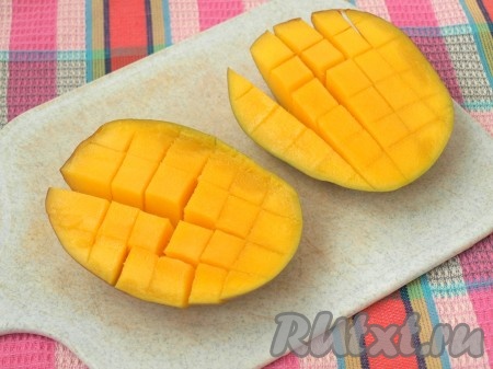 Манго разрезать на две половины, внутри срезать косточку. Мякоть прорезать ножом квадратиками до шкурки.
