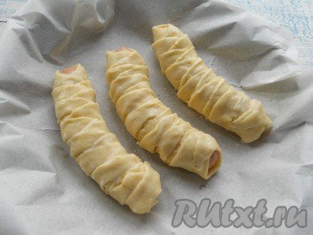 Сосиски в тесте поместить на противень (или в форму для запекания), застеленный бумагой для выпечки или смазанный маслом. Смазать тесто теплым молоком или желтком.
