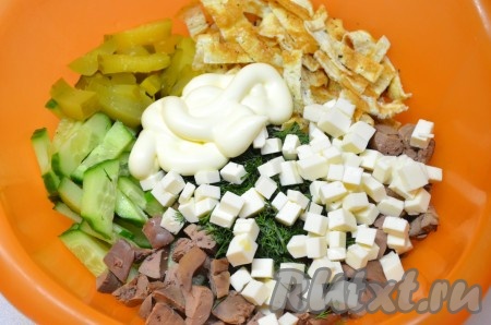 В миску выложить куриную печень, огурцы, сыр, яичные блинчики, нарезанную зелень, посолить, учитывая солёность огурцов, и поперчить, по желанию, добавить пропущенный через пресс чеснок. Заправить салат майонезом (или сметаной), перемешать.