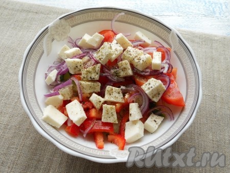 Затем добавить сыр "Фета" (или фетаксу, или брынзу), нарезанную на небольшие кубики. Посолить получившийся салат, посыпать специями (я посыпала чёрным молотым перцем и 0,5 чайной ложки сушёного орегано), влить лимонный сок и оливковое масло. Греческий салат аккуратно перемешать.