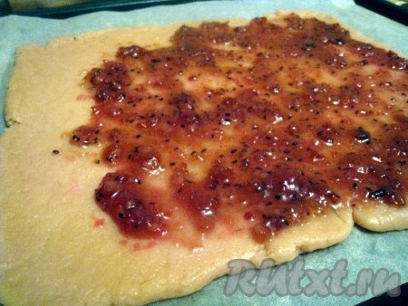 Тесто из холодильника раскатать в пласт толщиной около 1 см, выложить его на противень, застеленный бумагой (или смазанный маслом). Смазать тесто вареньем. У меня варенье из крыжовника с лимоном, подойдёт практически любое густое варенье, но лучше брать с кислинкой.
